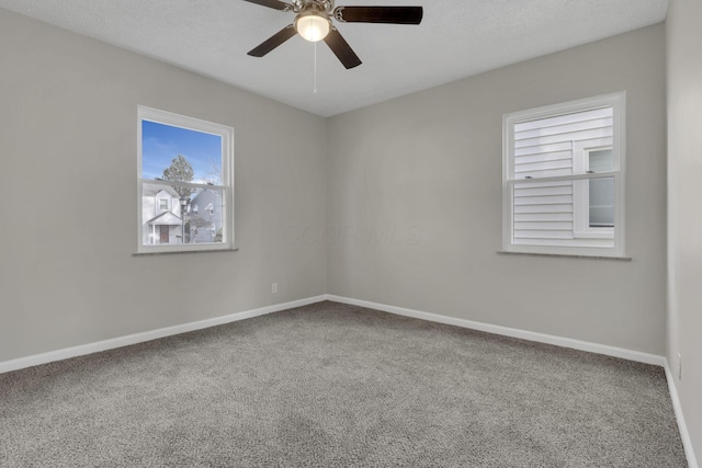 carpeted spare room with a textured ceiling, a ceiling fan, and baseboards