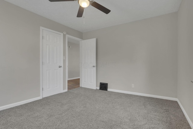 carpeted spare room featuring a textured ceiling, a ceiling fan, visible vents, and baseboards