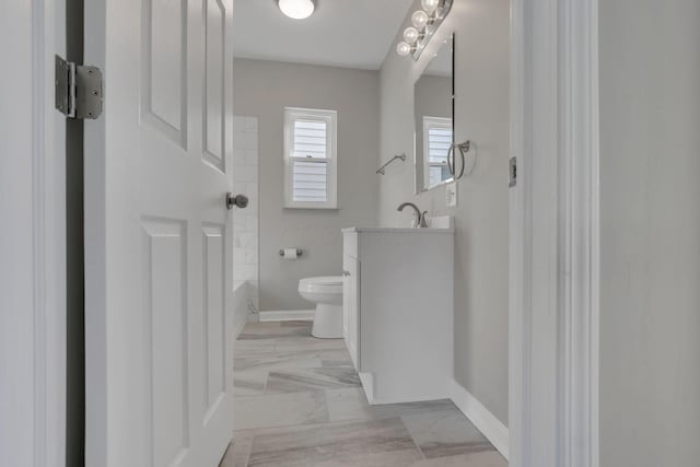 full bathroom featuring a tub to relax in, marble finish floor, toilet, vanity, and baseboards