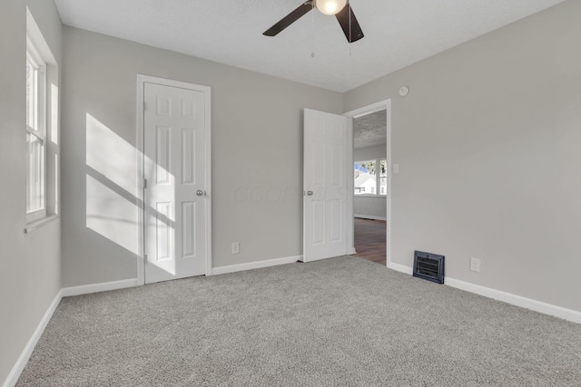 unfurnished bedroom featuring carpet floors, ceiling fan, visible vents, and baseboards