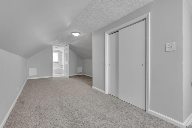 additional living space featuring carpet floors, vaulted ceiling, a textured ceiling, and baseboards