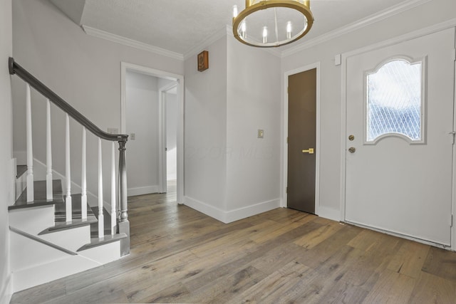 foyer entrance with a chandelier, baseboards, stairs, ornamental molding, and wood-type flooring