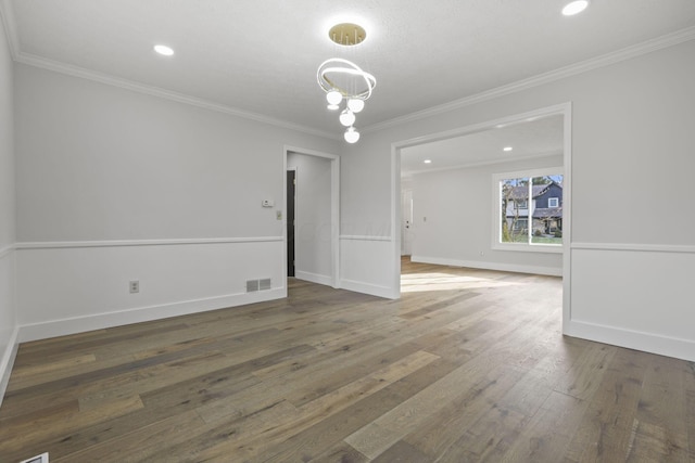 empty room with visible vents, crown molding, baseboards, and hardwood / wood-style flooring