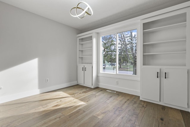 unfurnished dining area with hardwood / wood-style flooring, baseboards, and visible vents