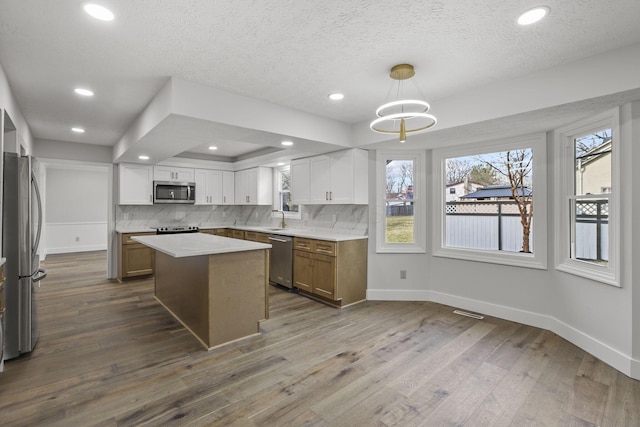 kitchen with dark wood-style floors, tasteful backsplash, appliances with stainless steel finishes, a sink, and baseboards