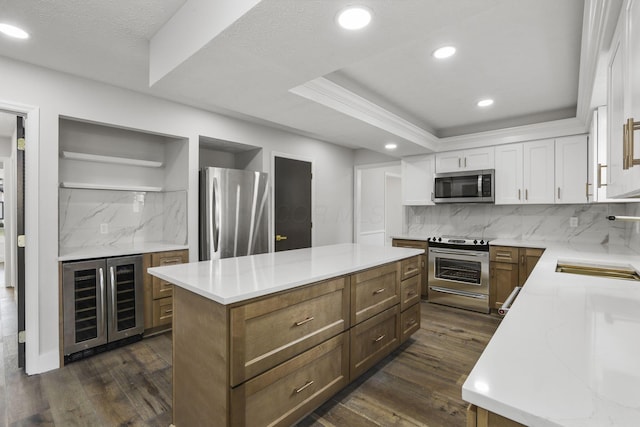 kitchen featuring a raised ceiling, a kitchen island, appliances with stainless steel finishes, dark wood-style flooring, and open shelves