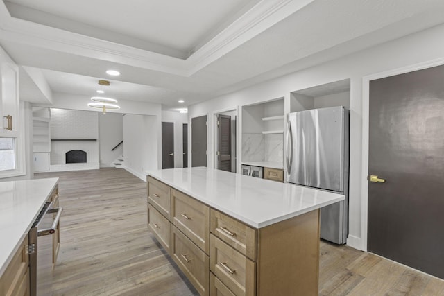 kitchen featuring light wood-type flooring, a tray ceiling, open floor plan, and freestanding refrigerator