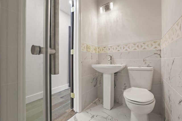 bathroom featuring a wainscoted wall, marble finish floor, a sink, and toilet