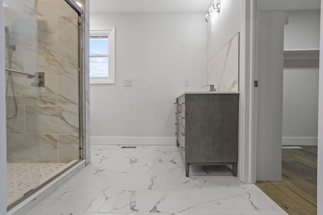 bathroom with marble finish floor, a marble finish shower, baseboards, and vanity