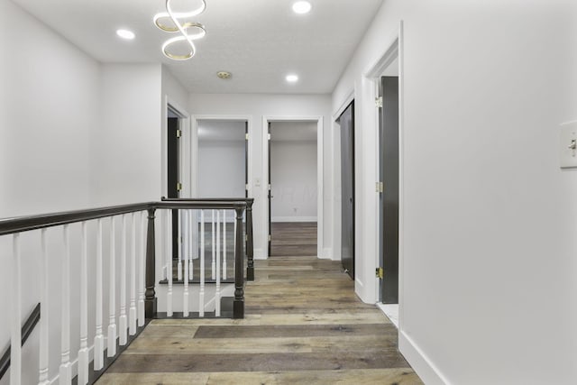 corridor with an upstairs landing, recessed lighting, baseboards, and wood finished floors