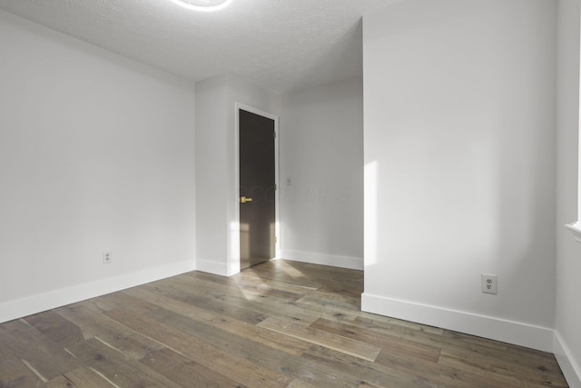 spare room featuring a textured ceiling, wood-type flooring, and baseboards