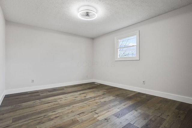 empty room featuring a textured ceiling, dark wood-type flooring, and baseboards