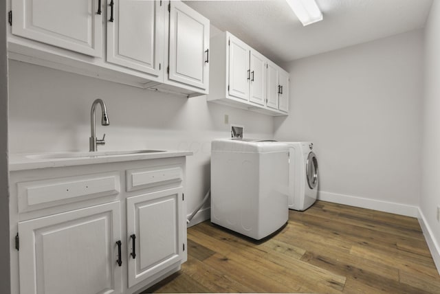 washroom featuring hardwood / wood-style flooring, cabinet space, a sink, and washer / dryer