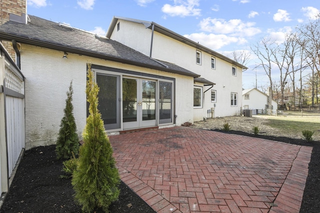 rear view of property featuring a patio, a chimney, stucco siding, a shingled roof, and cooling unit