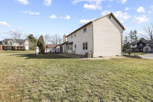 back of property with central AC, a lawn, and stucco siding