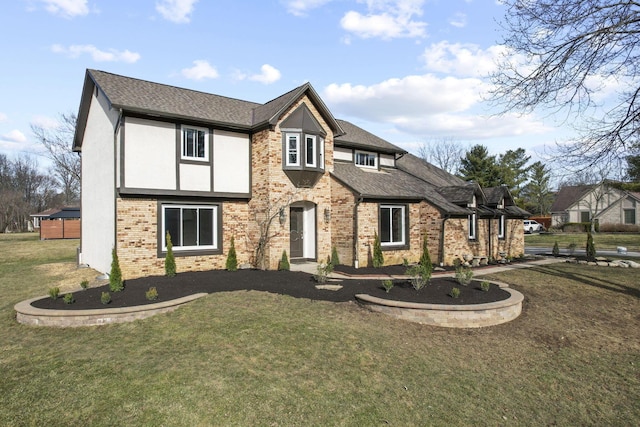 tudor home with a shingled roof, brick siding, a front lawn, and stucco siding