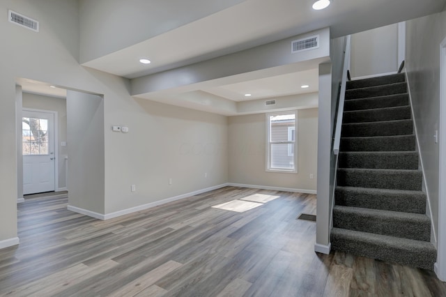 interior space with baseboards, stairs, visible vents, and wood finished floors