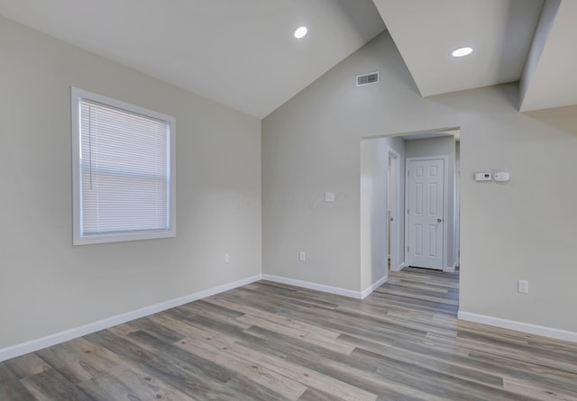 unfurnished room featuring baseboards, visible vents, wood finished floors, vaulted ceiling, and recessed lighting