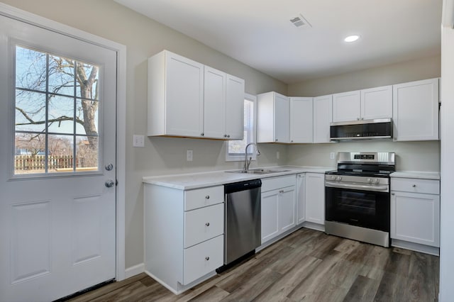 kitchen featuring dark wood-style floors, stainless steel appliances, light countertops, white cabinets, and a sink