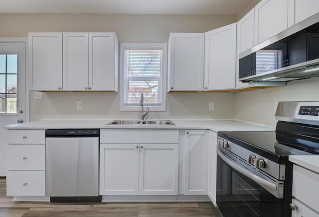 kitchen featuring stainless steel appliances, light countertops, light wood-style floors, white cabinets, and a sink