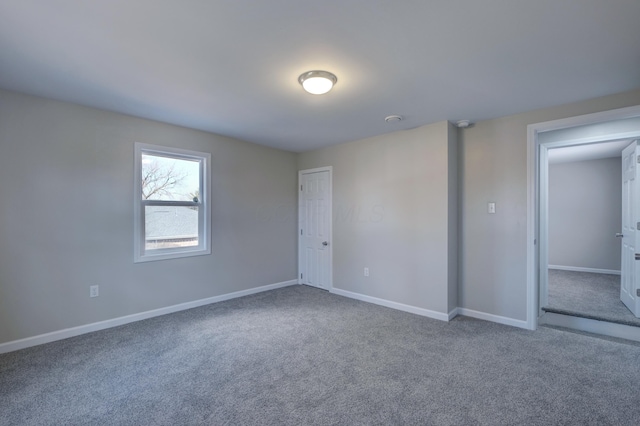 unfurnished room featuring carpet floors and baseboards