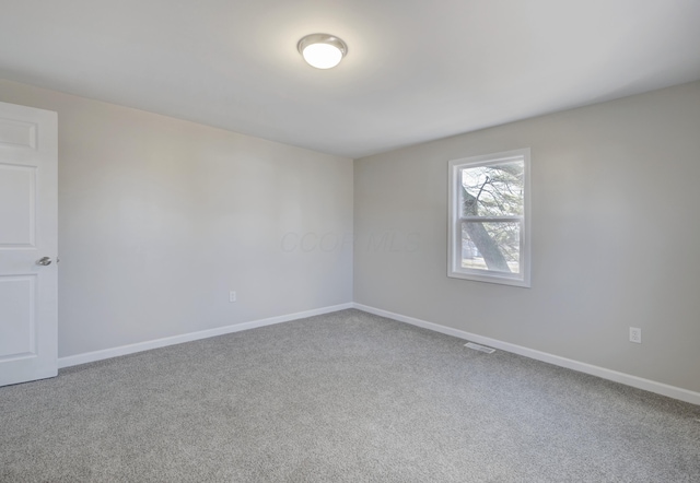 carpeted empty room featuring baseboards