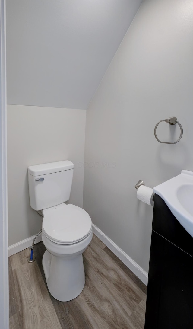 bathroom featuring vaulted ceiling, wood finished floors, toilet, and baseboards