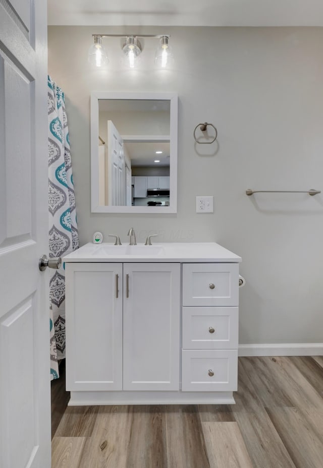 bathroom featuring wood finished floors, vanity, and baseboards