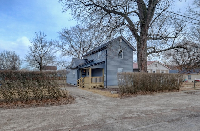 view of side of property with metal roof and driveway