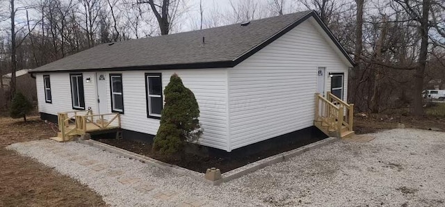 view of side of property featuring roof with shingles and driveway