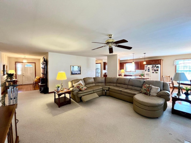 living room featuring plenty of natural light, light colored carpet, and a ceiling fan