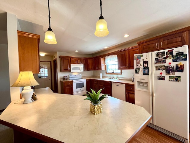 kitchen featuring white appliances, a peninsula, a sink, hanging light fixtures, and light countertops