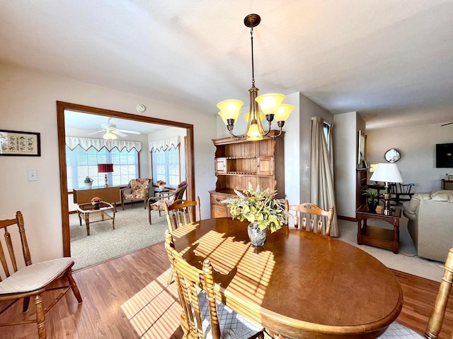 dining area featuring ceiling fan with notable chandelier and wood finished floors