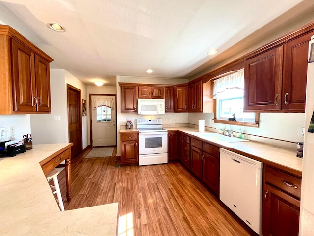 kitchen featuring light wood-style flooring, a sink, recessed lighting, white appliances, and light countertops