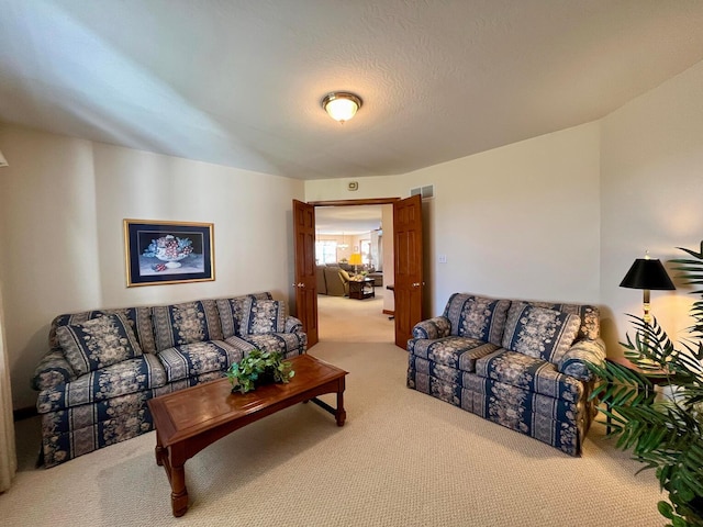 carpeted living room with visible vents and a textured ceiling