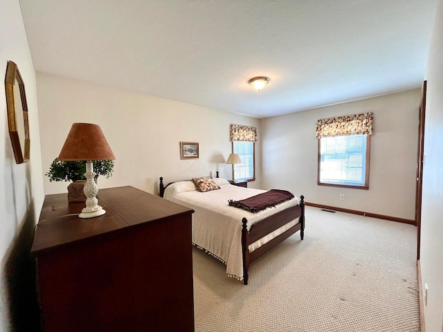 bedroom featuring visible vents, light colored carpet, and baseboards