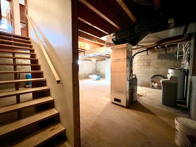 unfinished basement featuring water heater, heating unit, and stairs