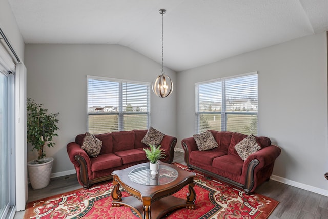 living area featuring a chandelier, lofted ceiling, plenty of natural light, and wood finished floors