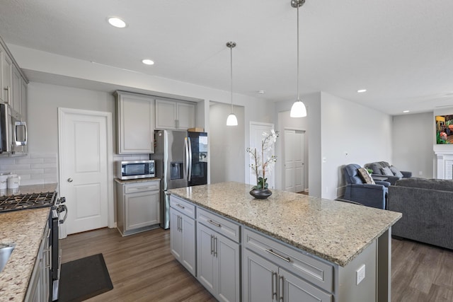 kitchen featuring stainless steel appliances, tasteful backsplash, gray cabinetry, dark wood-type flooring, and open floor plan