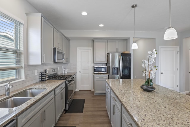 kitchen with stainless steel appliances, tasteful backsplash, gray cabinetry, dark wood-type flooring, and a sink