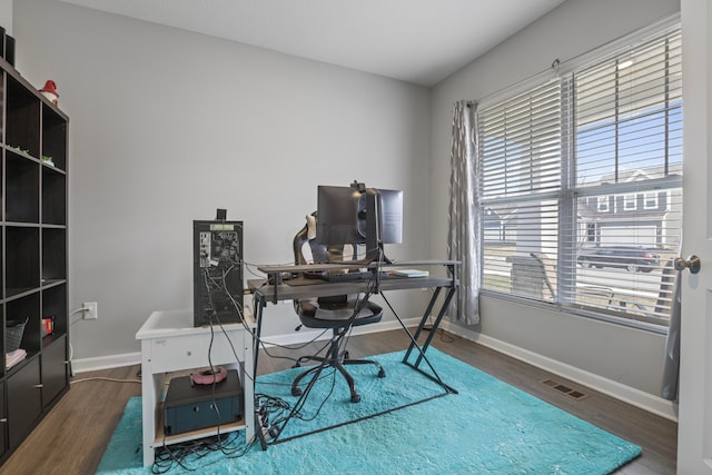 home office with wood finished floors, visible vents, and baseboards