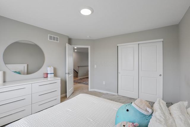 bedroom with baseboards, visible vents, a closet, and light colored carpet