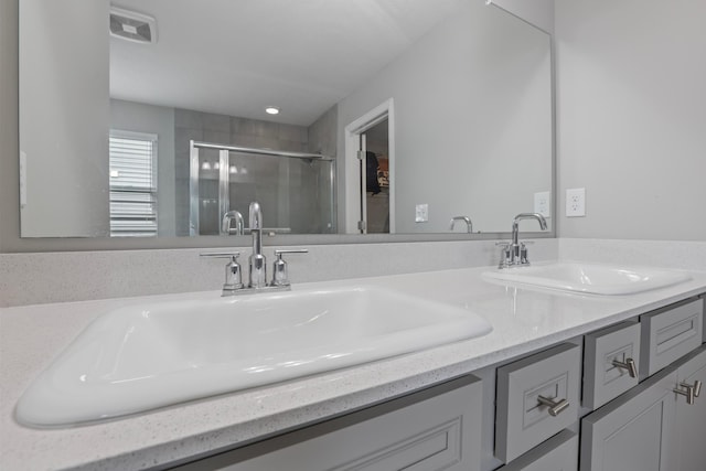 bathroom featuring double vanity, a stall shower, and a sink