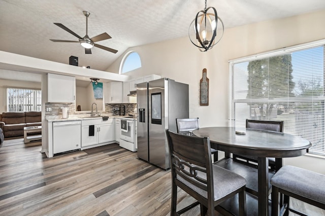 kitchen featuring white appliances, a sink, white cabinets, light countertops, and light wood finished floors