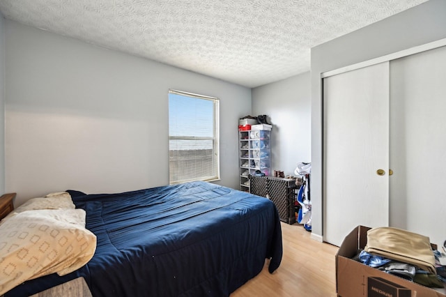 bedroom featuring light wood-style floors, a closet, and a textured ceiling