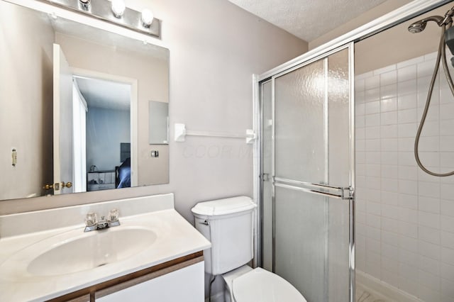 full bath featuring a stall shower, connected bathroom, toilet, a textured ceiling, and vanity