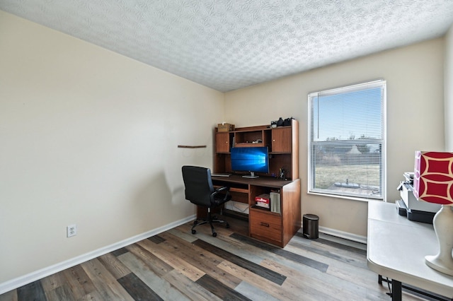 home office with a textured ceiling, baseboards, and wood finished floors