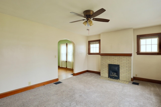 unfurnished living room featuring carpet, visible vents, arched walkways, and baseboards