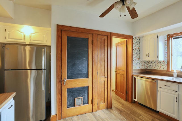 kitchen with light wood-style flooring, a sink, white cabinets, light countertops, and appliances with stainless steel finishes