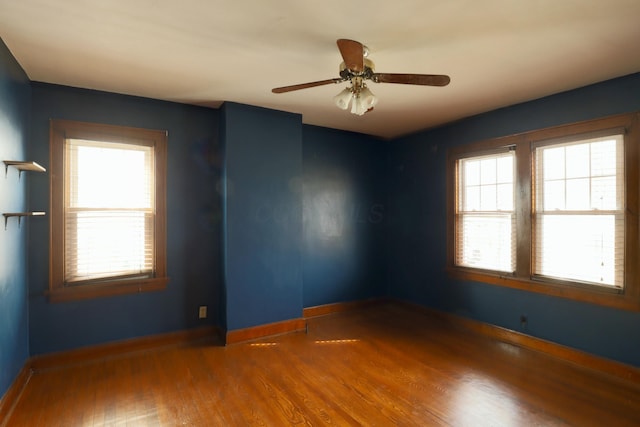 unfurnished room with a healthy amount of sunlight, a ceiling fan, baseboards, and wood finished floors